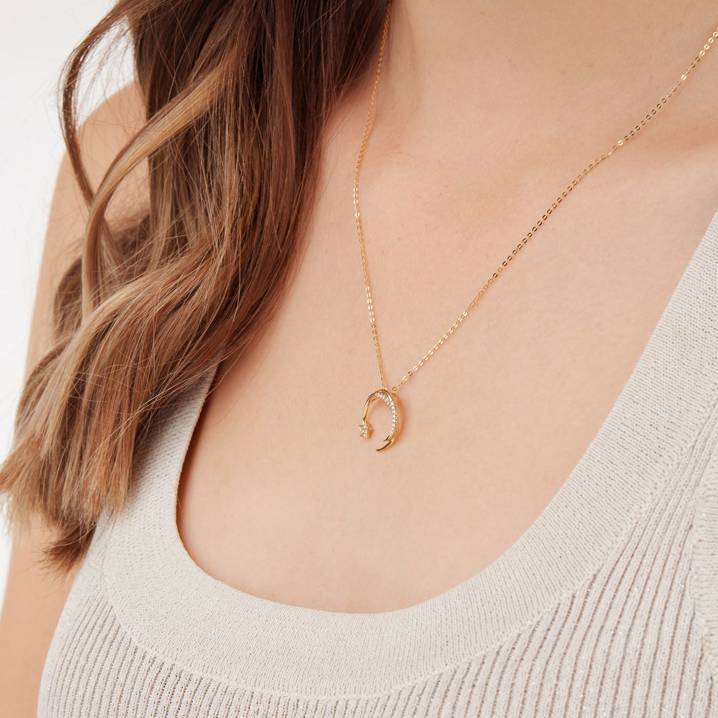 Gold necklace with a falling star shaped diamond studded pendant worn by a woman